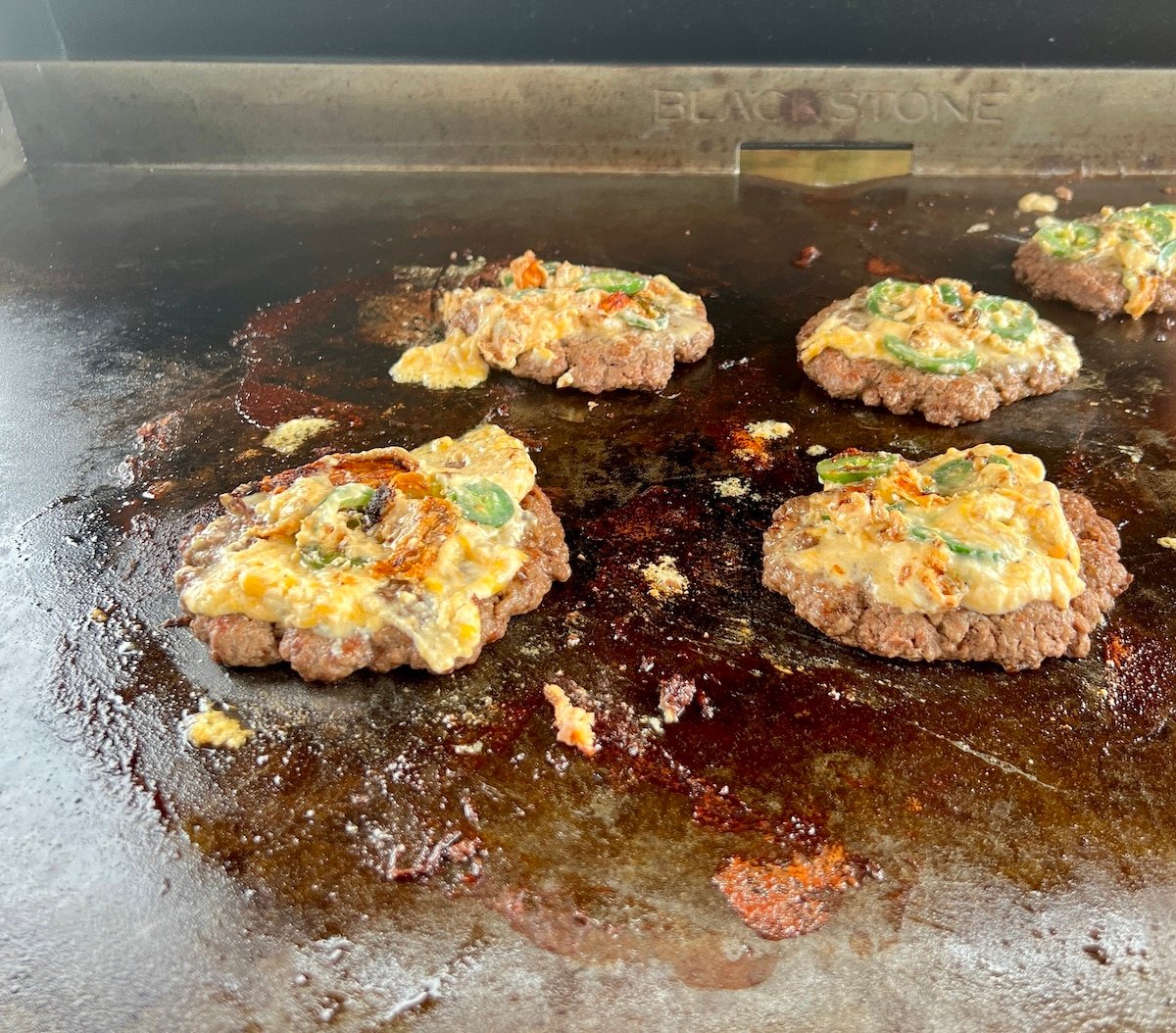Burgers with popper topping on griddle.