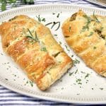 Chicken wellington on a platter with fresh herbs.
