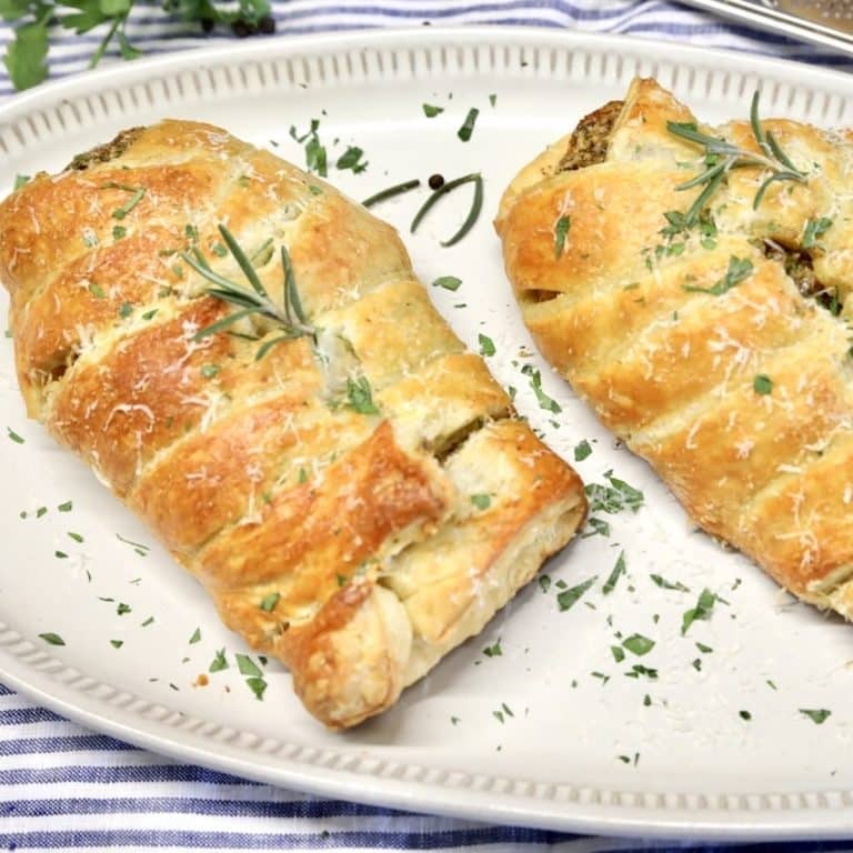 Chicken wellington on a platter with fresh herbs.