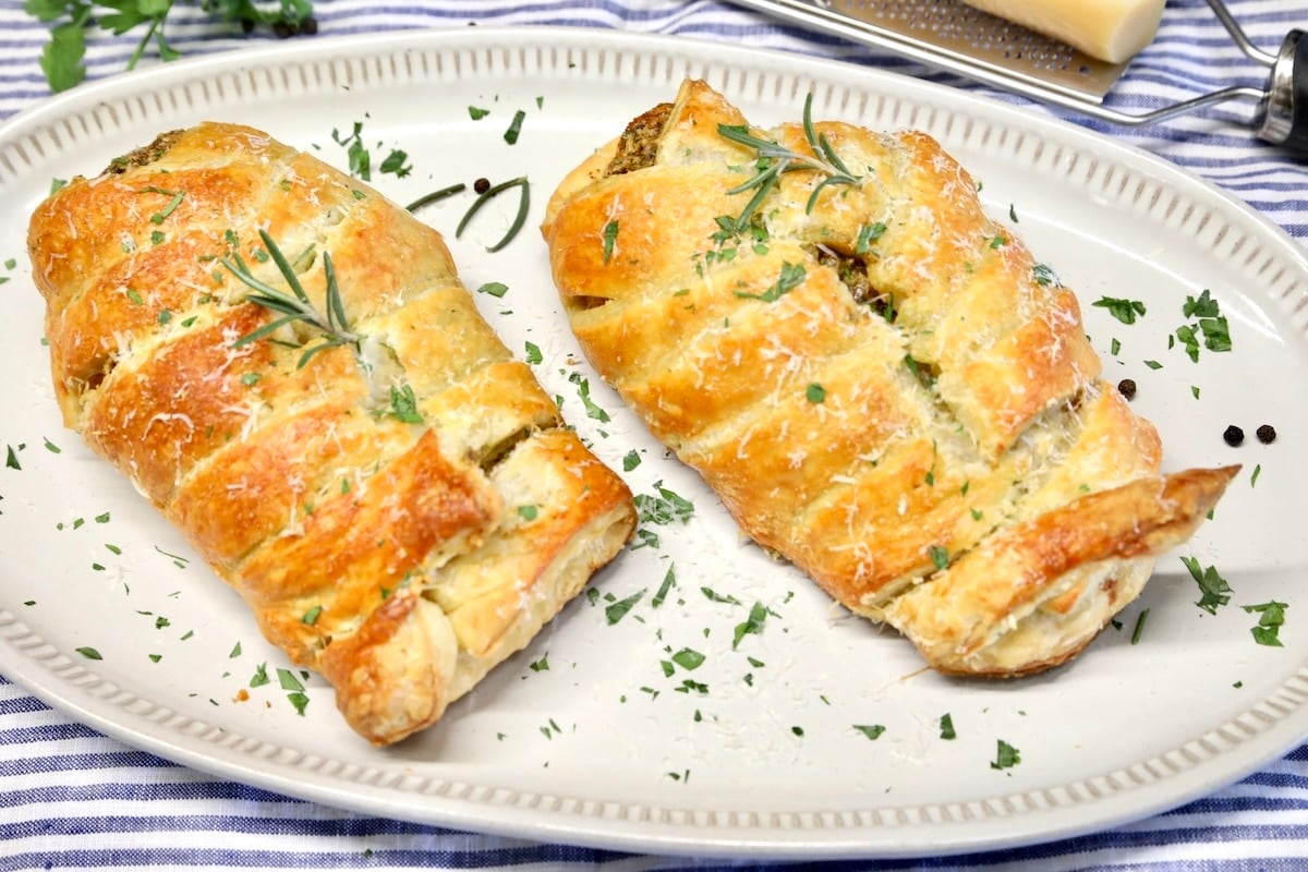 Puff pastry chicken recipe with rosemary pesto. Platter with 2 chicken breasts wrapped in puff pastry.