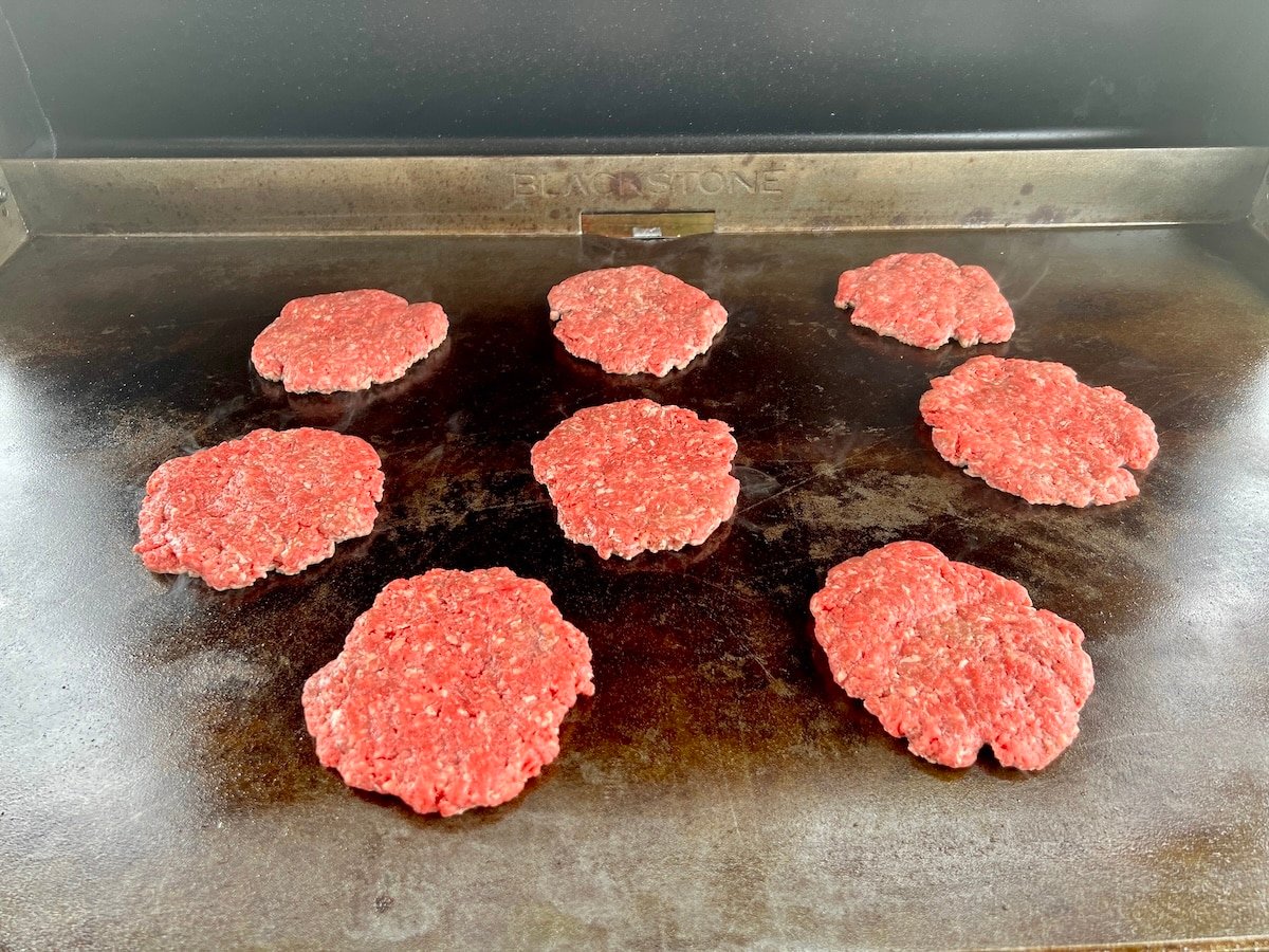 Hamburger patties on a blackstone griddle.