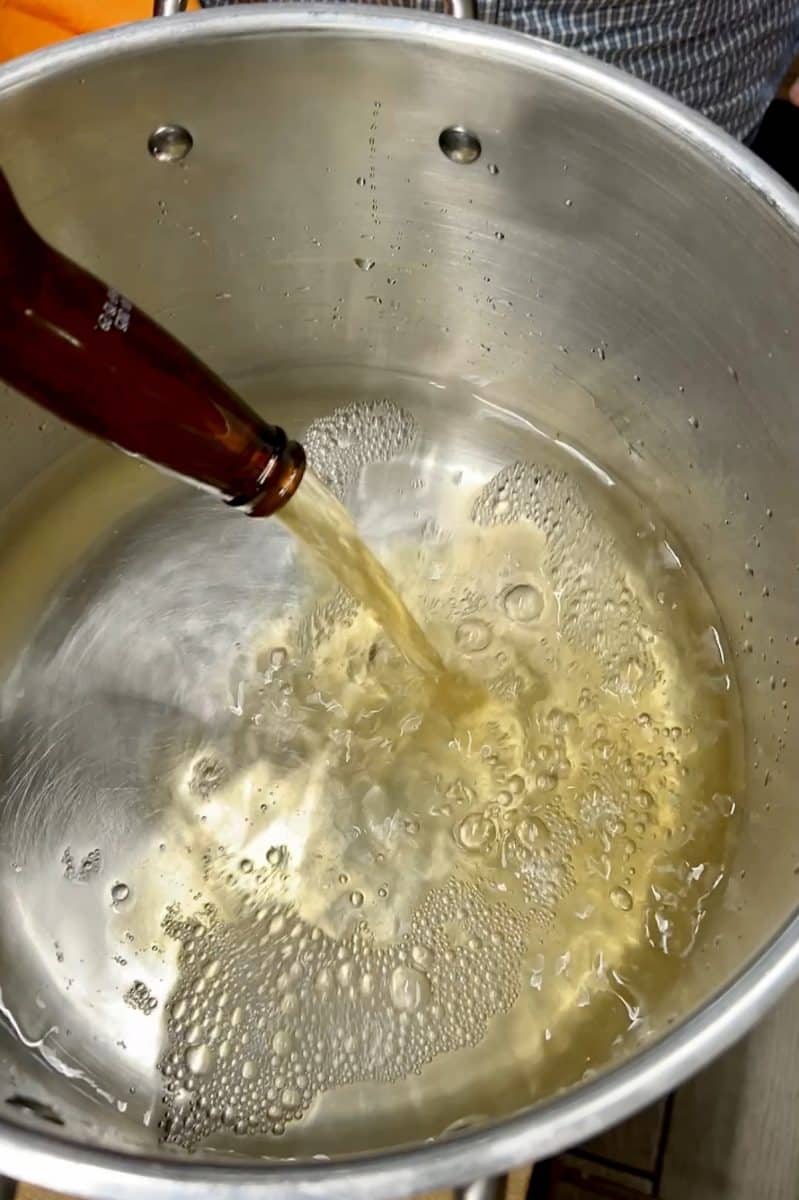 Adding beer to seafood boil broth.