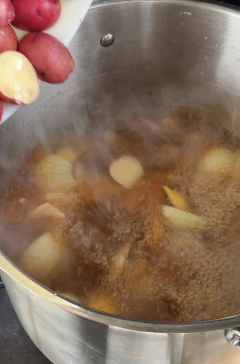 Adding potatoes to low country boil pot.