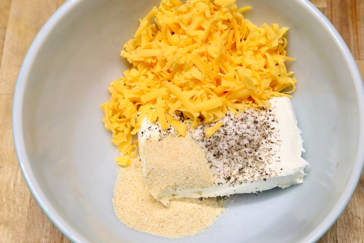 Cream cheese, shredded cheddar, seasonings in a bowl.