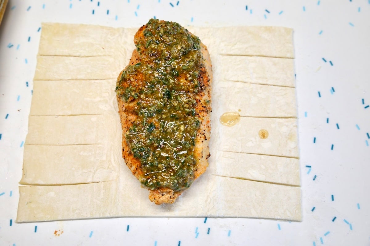 Chicken breast topped with pesto on sheet of pesto.