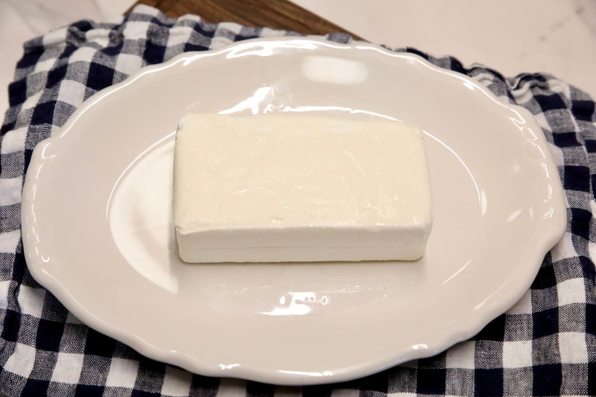 Block of cream cheese on a plate.