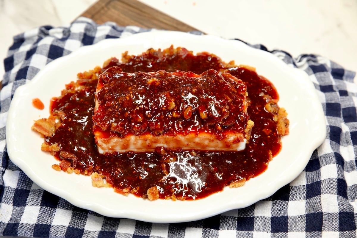 Raspberry chipotle sauce over block of cream cheese on a platter.