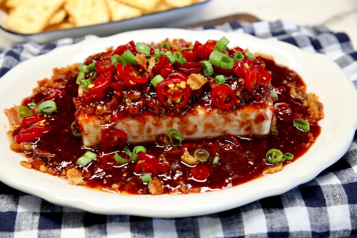 Platter of cream cheese appetizer topped with raspberry chipotle sauce and jalapenos.