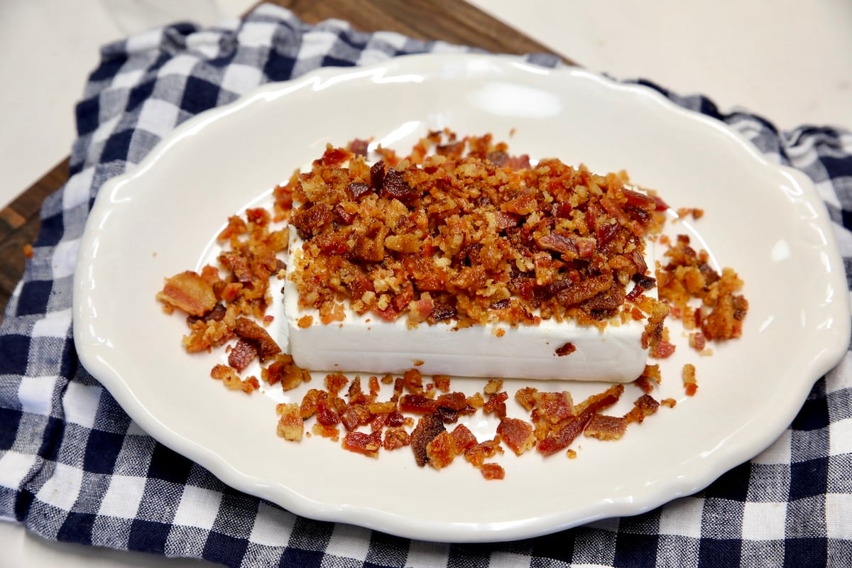 Bacon crumbles on block of cream cheese.