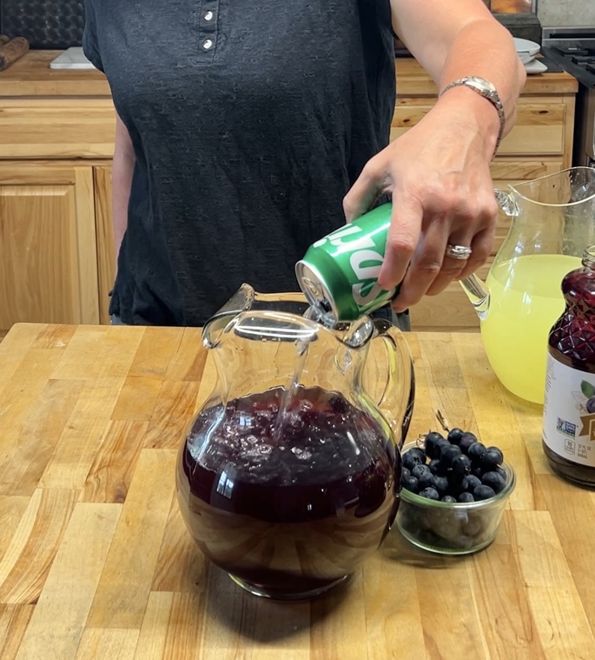 Pouring sprite into punch pitcher.