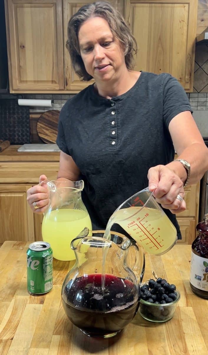 Pouring lemonade into a pitcher for punch.