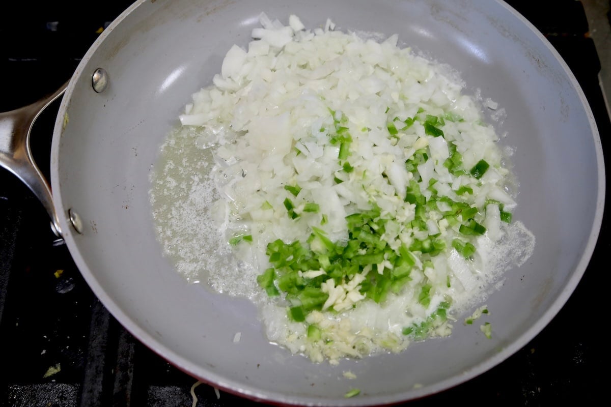 Cooking onions, jalapenos and garlic in a pan with butter.