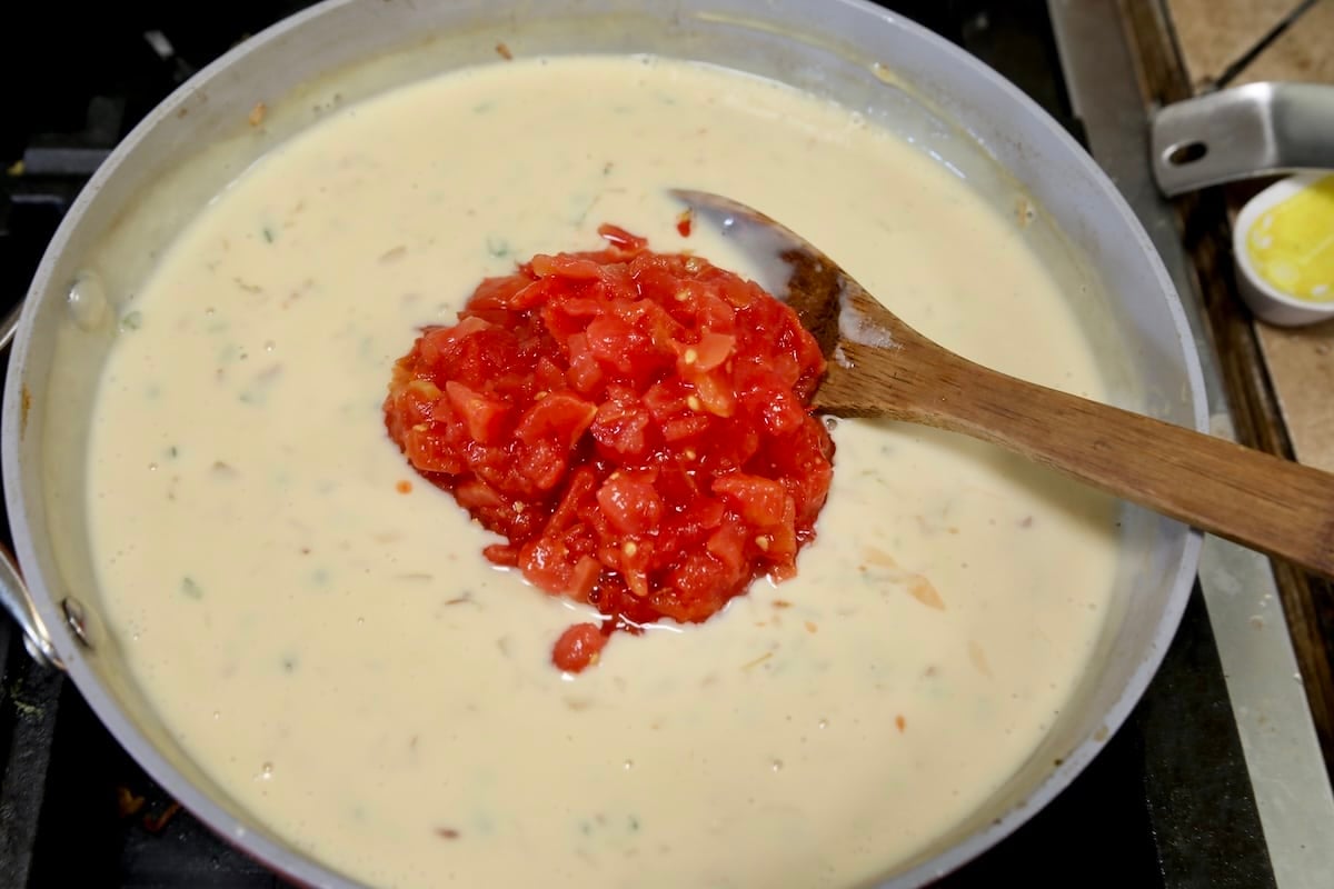 Adding rotel tomatoes to white cheese dip.