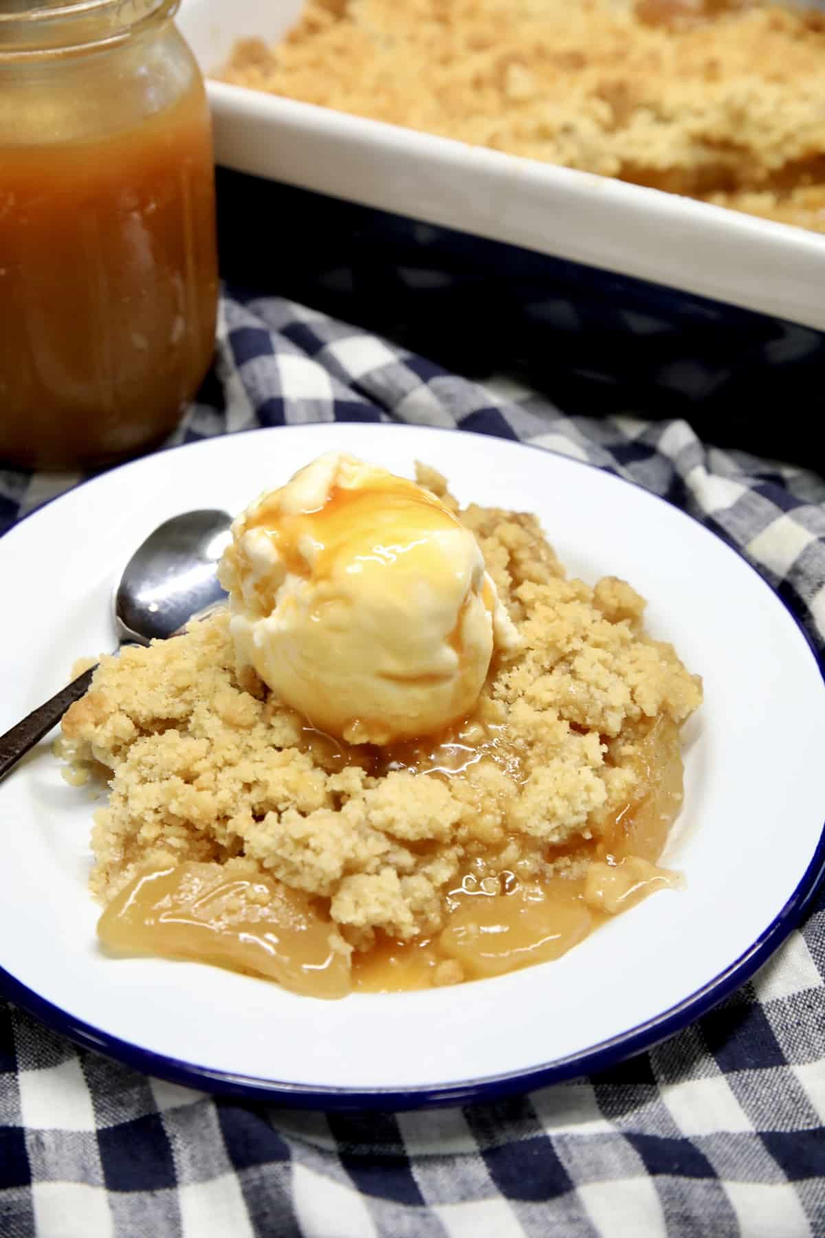 Apple crumble on a plate with ice cream and caramel.