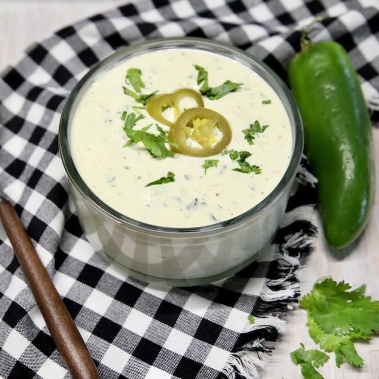 Bowl of jalapeno ranch with cilantro and 2 jalapeno slices.
