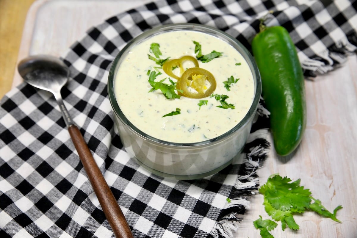 Bowl of jalapeno ranch, spoon, whole jalapeno.