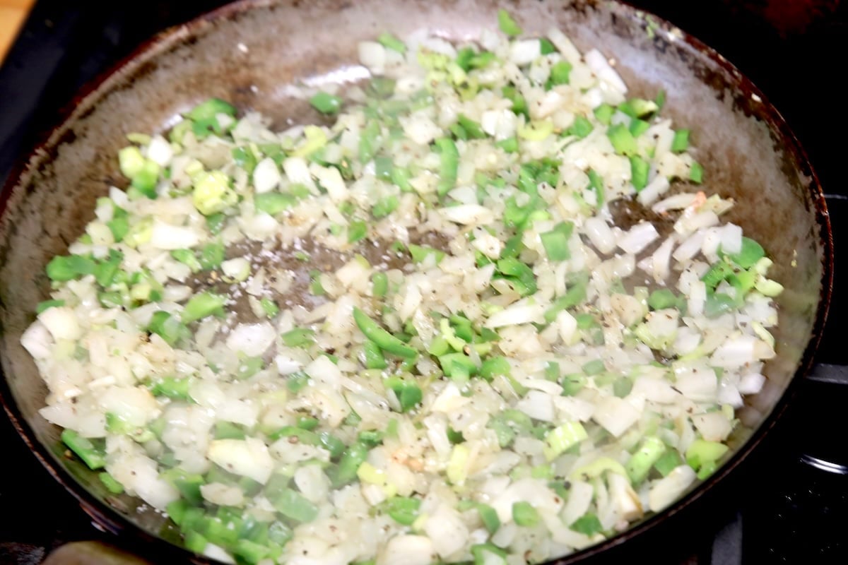 Cooking onions and peppers in a skillet.