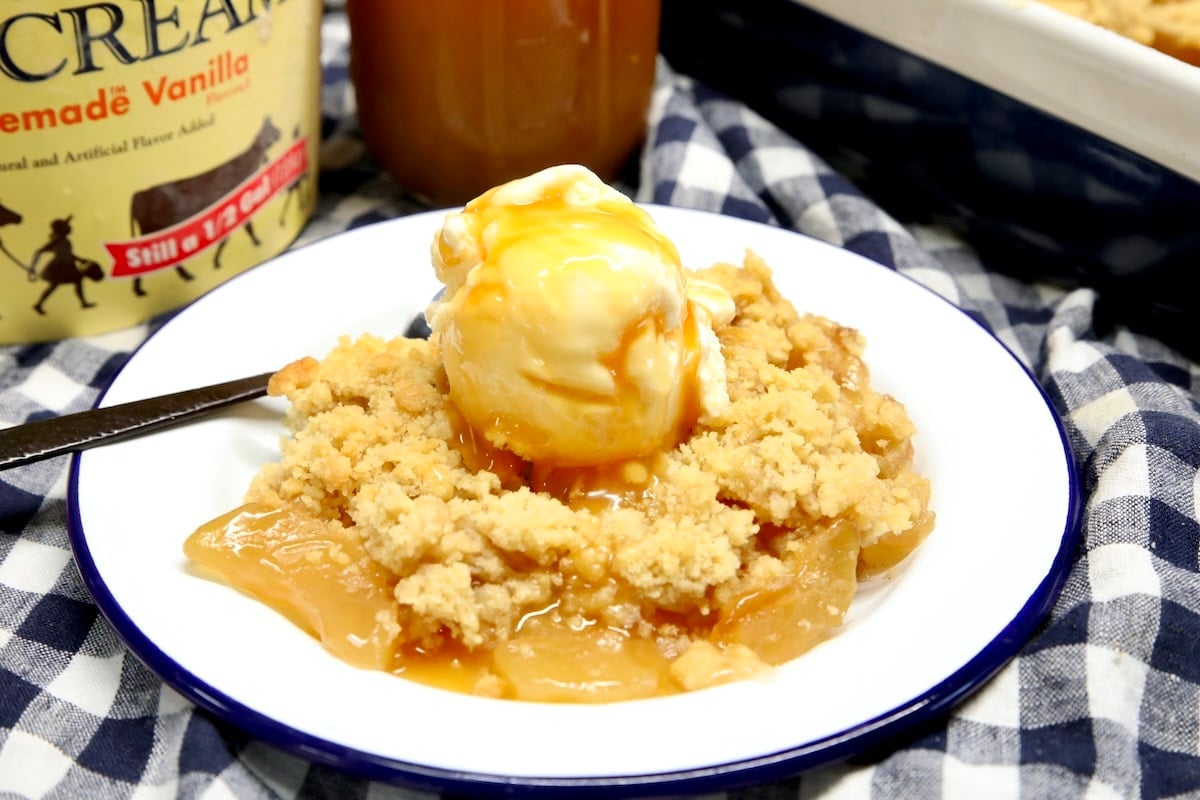 Apple pie crumble with caramel. Caramel apple crumble on a plate with scoop of vanilla ice cream and caramel sauce.