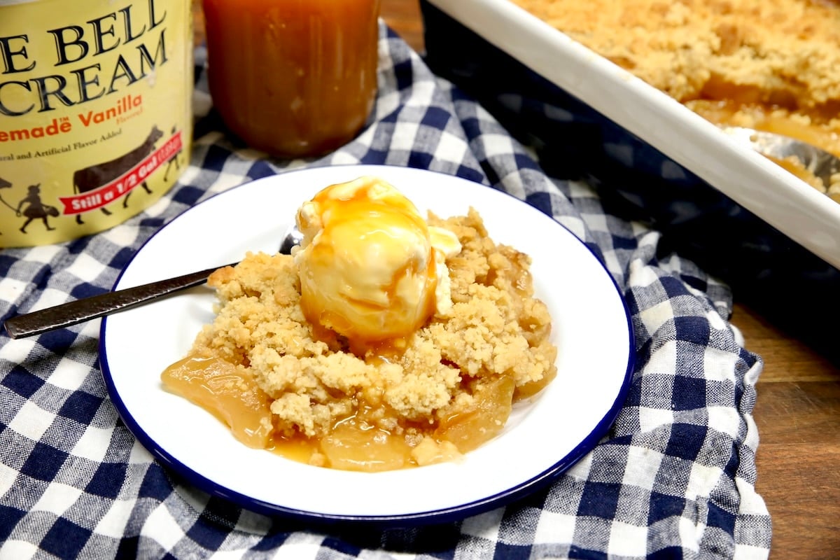 Plate of apple crumble with ice cream and caramel sauce.