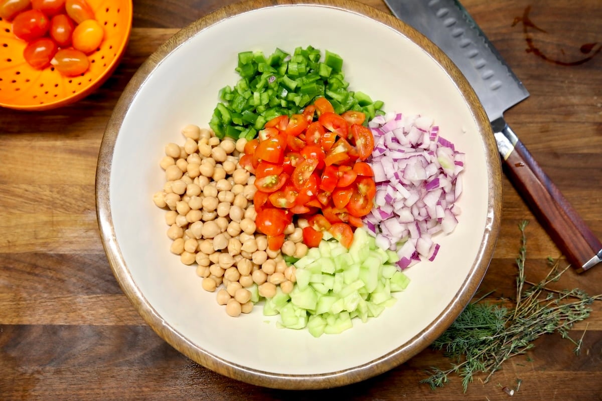 Bowl of chickpeas, tomatoes, cucumbers, red onion, bell pepper.