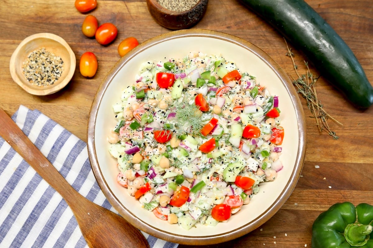 Bowl of chickpea salad with cucumbers and tomatoes.