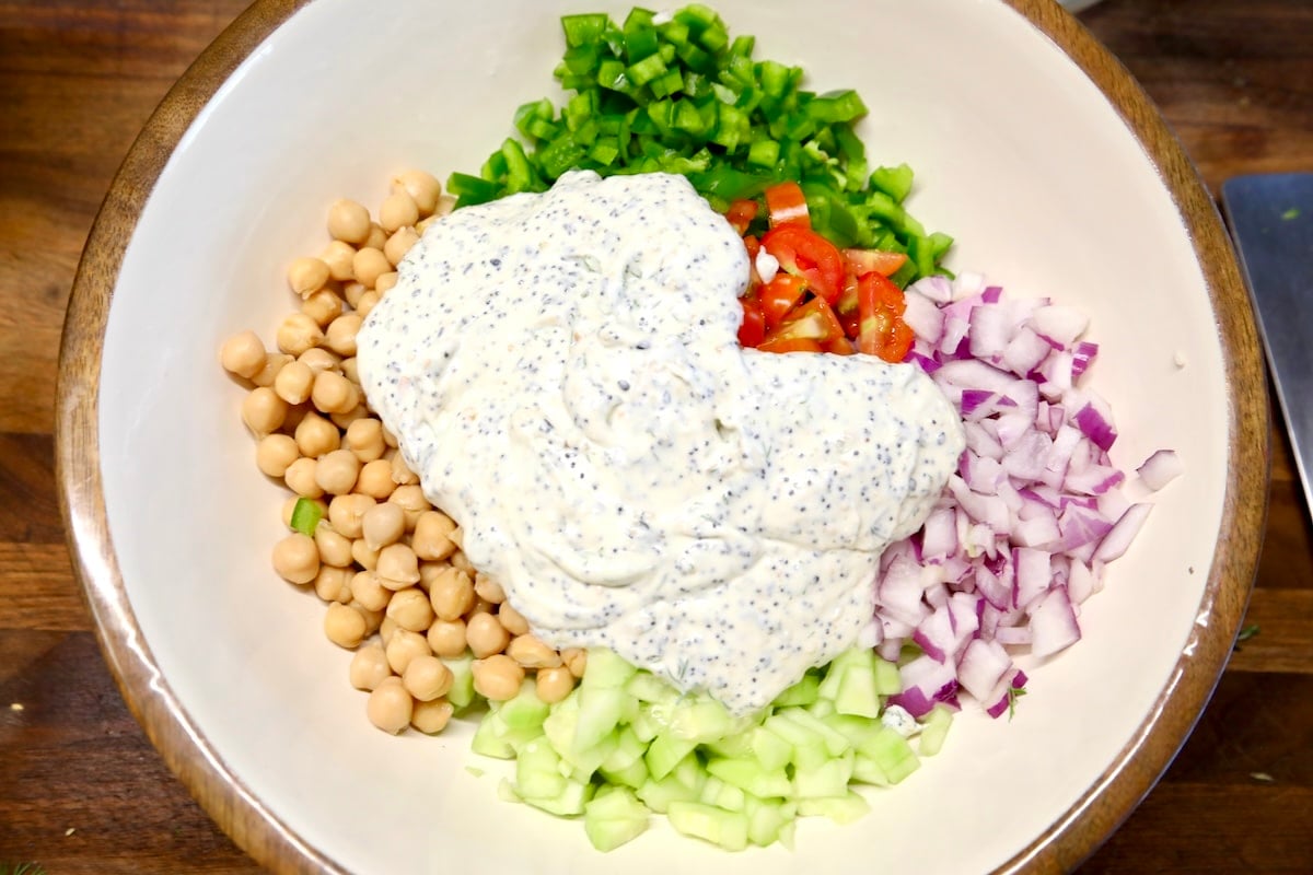 Bowl of chickpea vegetable salad with creamy dressing.