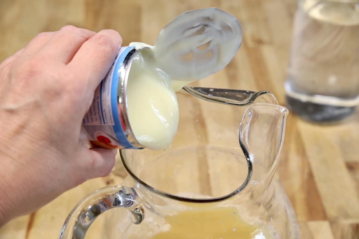 Pouring sweetened condensed milk into a pitcher.