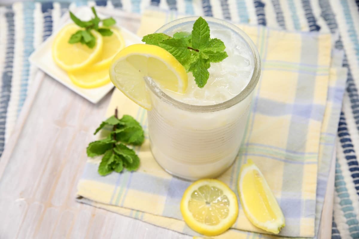 Glass of creamy lemonade with lemon and mint garnish.