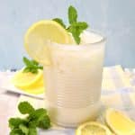 Glass of creamy lemonade with lemon and mint garnish.