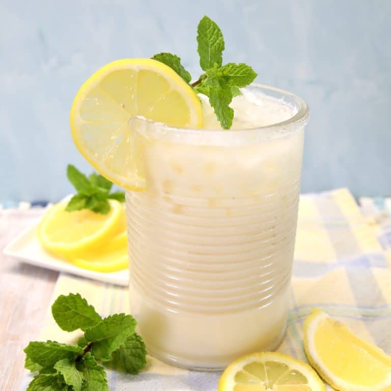 Glass of creamy lemonade with lemon and mint garnish.