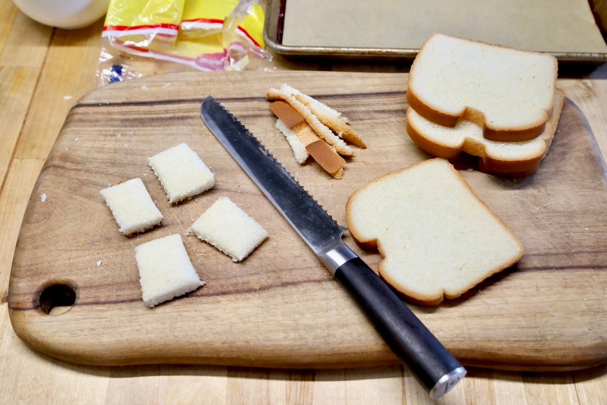 Cutting bread slices for cheese dreams on a cutting board.