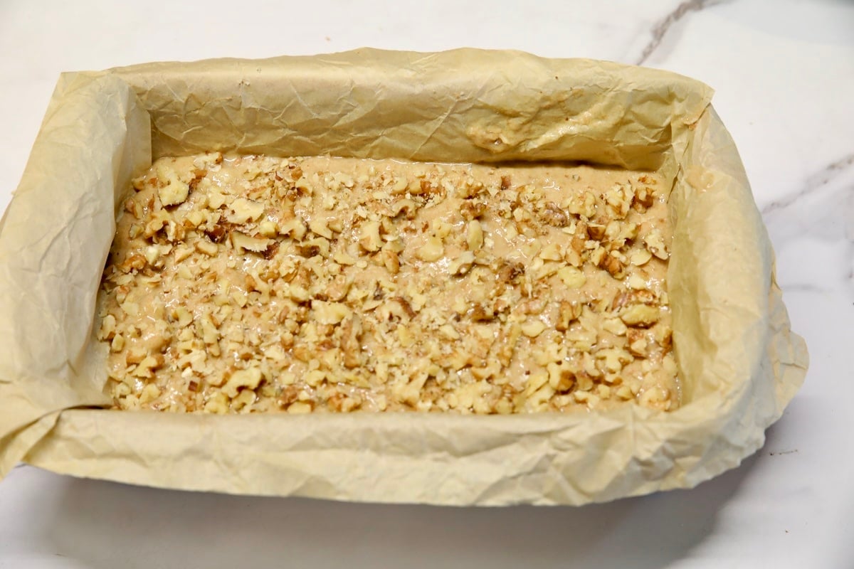 Banana bread batter in parchment lined loaf pan.