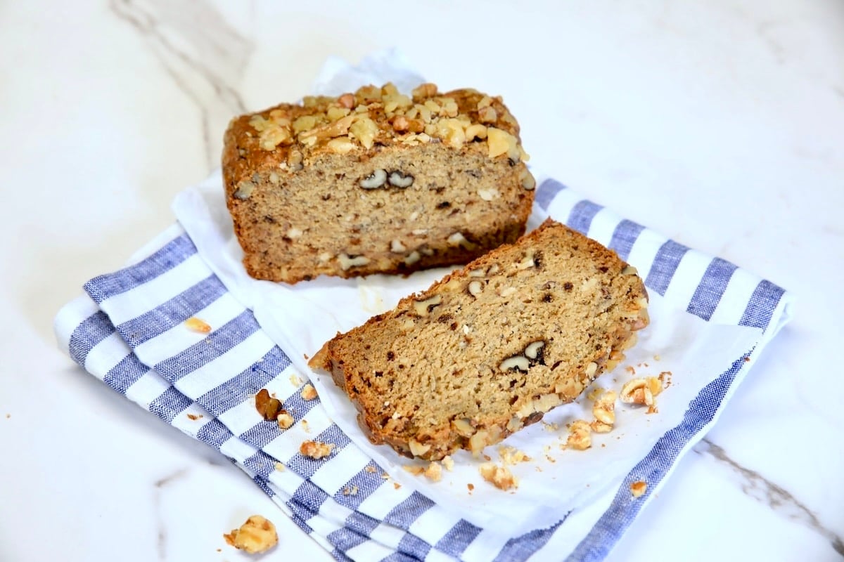 Banana walnut loaf made without sugar. Loaf of banana bread with slice on striped napkin.