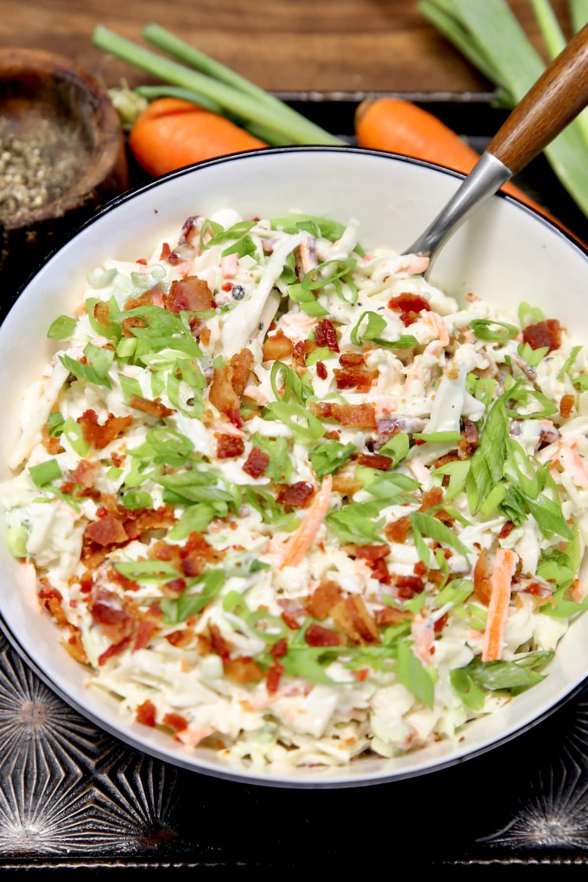 Bowl of bacon ranch coleslaw with a spoon.