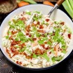 Bowl of coleslaw with bacon and green onions.