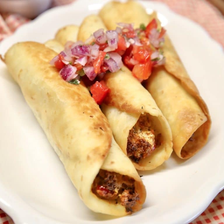 Plate of 3 taquitos with pico de gallo on top.