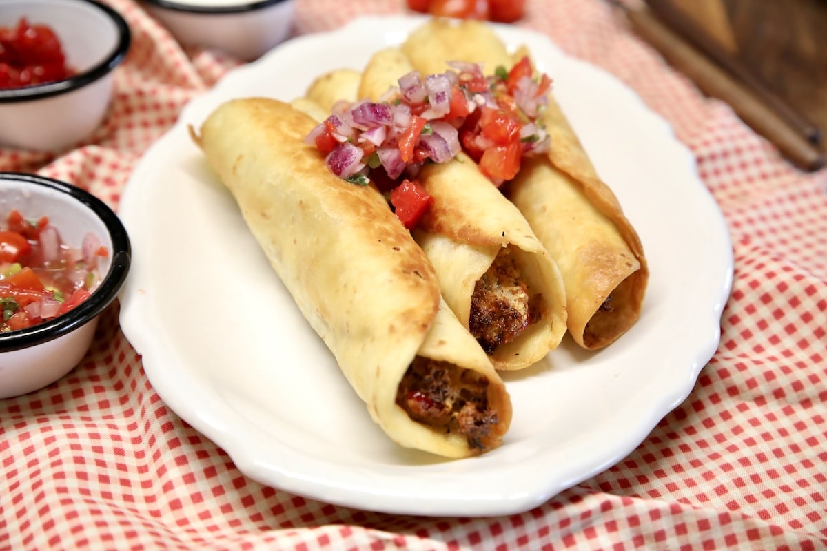 Brisket jalapeno popper taquitos on a plate.