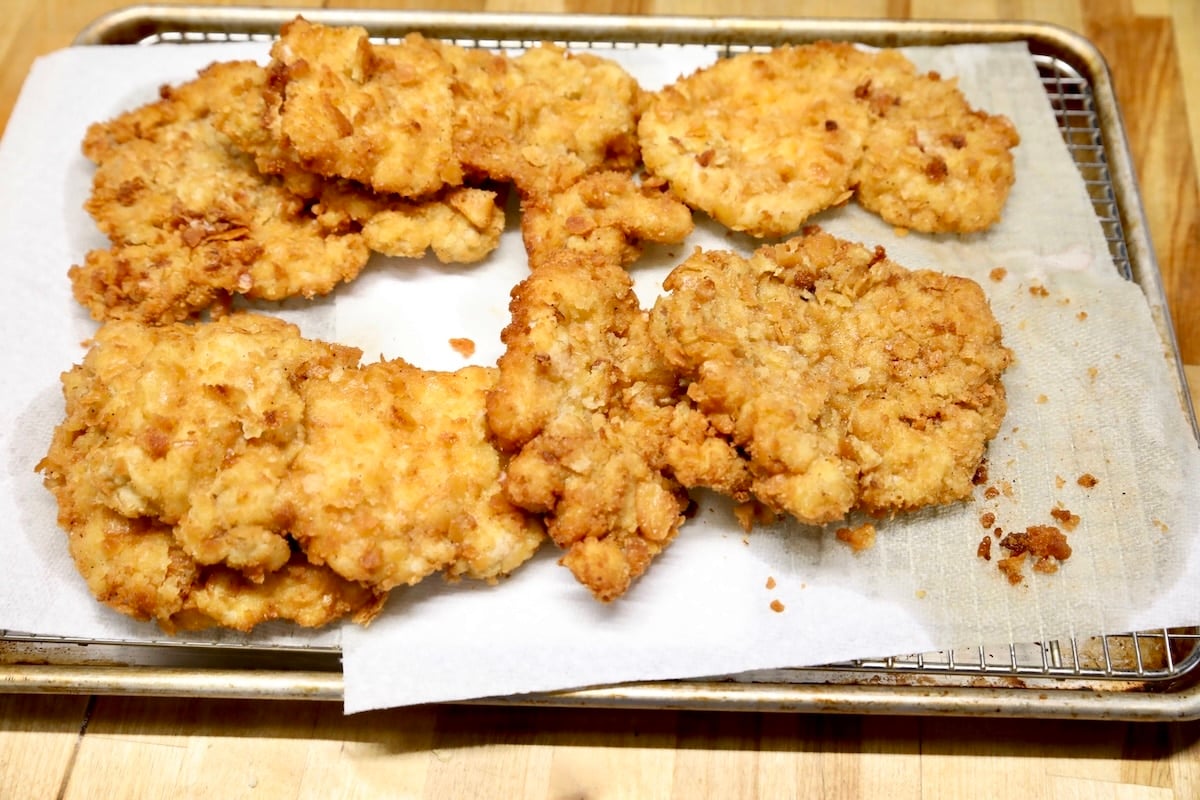 Breaded pork chops draining on paper towel.