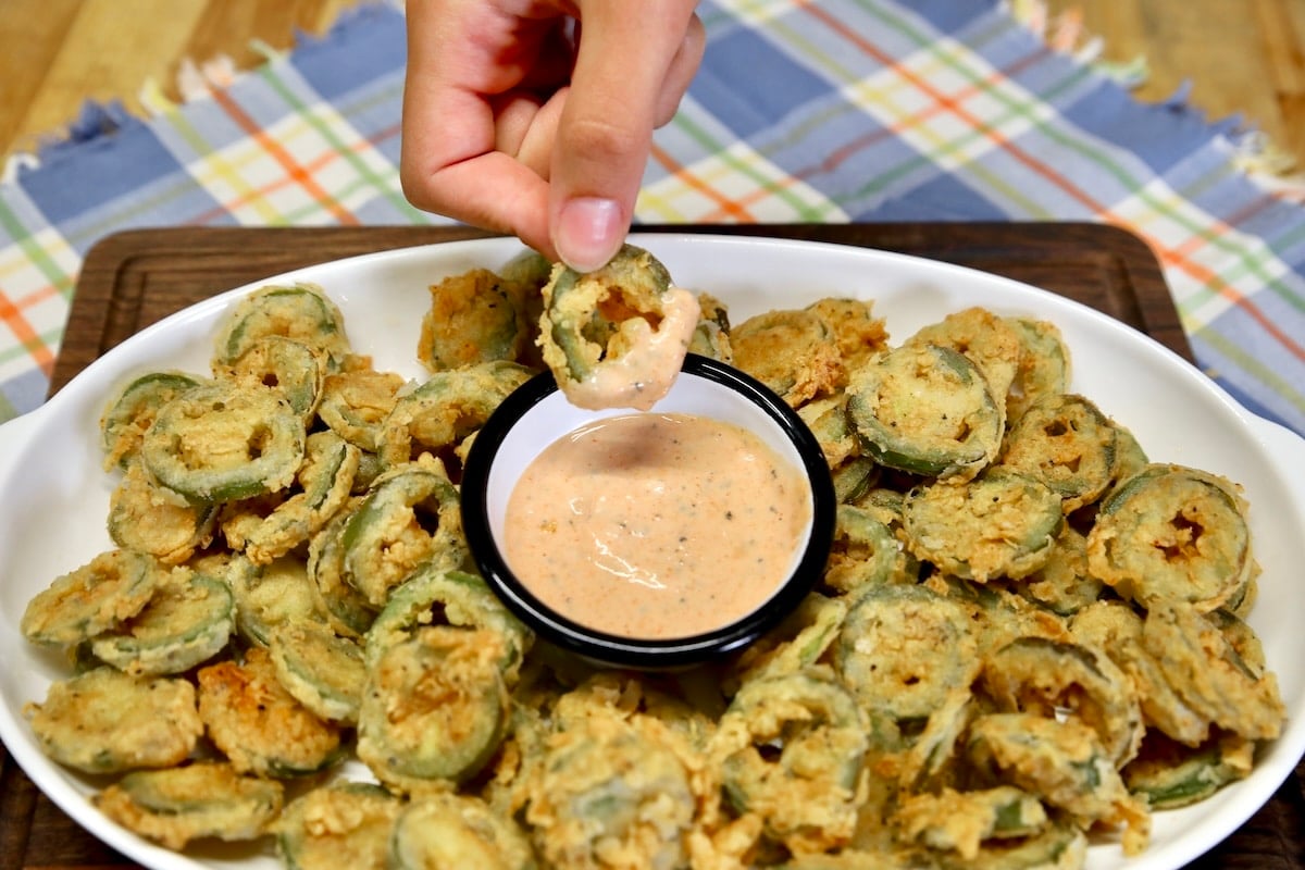 Dipping fried jalapenos slice into blooming onion sauce.