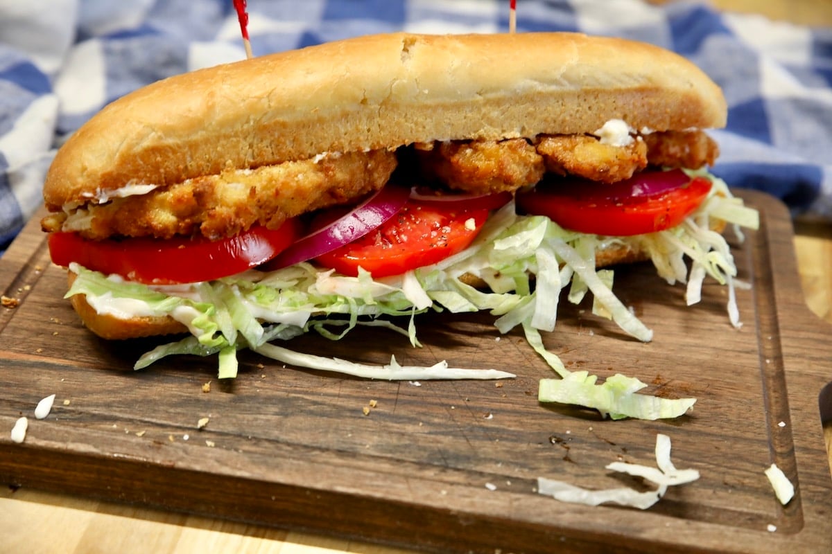 Fried pork chop sandwich with lettuce, onion and tomato. Fried pork chop sandwich on a hoagie bun with lettuce & tomato.