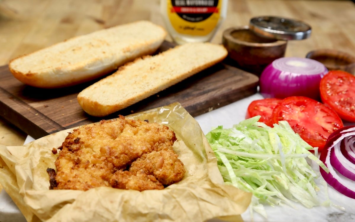 Fried pork chop, hoagie bun scliedd in half, mayo, lettuce, tomato, red onion.