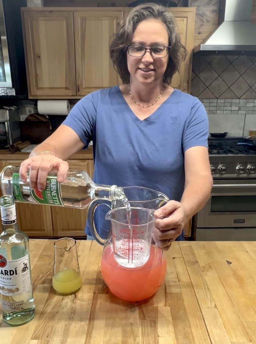Pouring watermelon vodka into measuring cup.