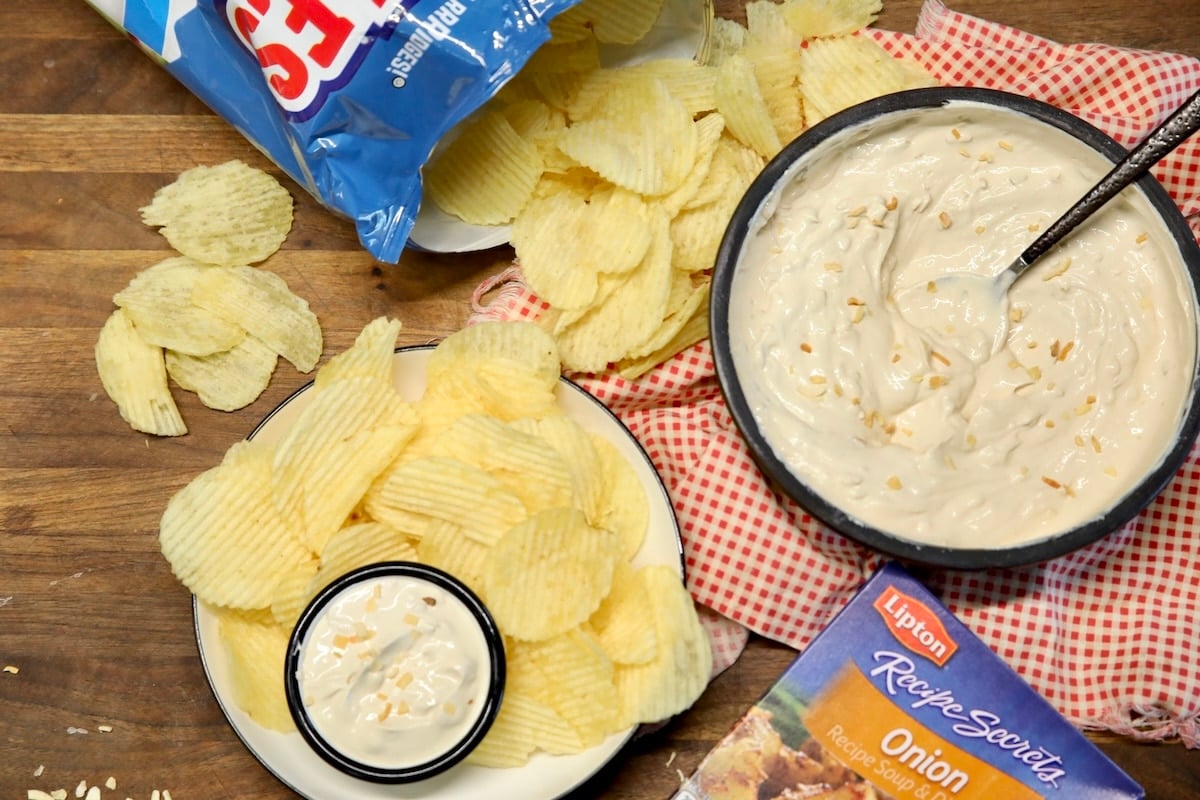 Bowl of onion soup mix dip, ruffles chips with small dipping bowl.