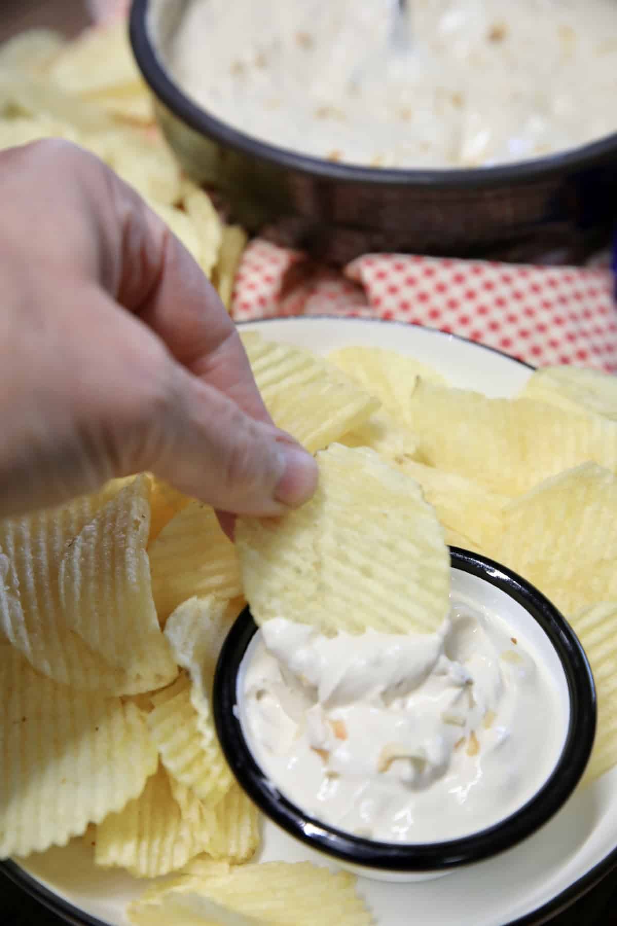 Chip dipping into small bowl of onion dip.