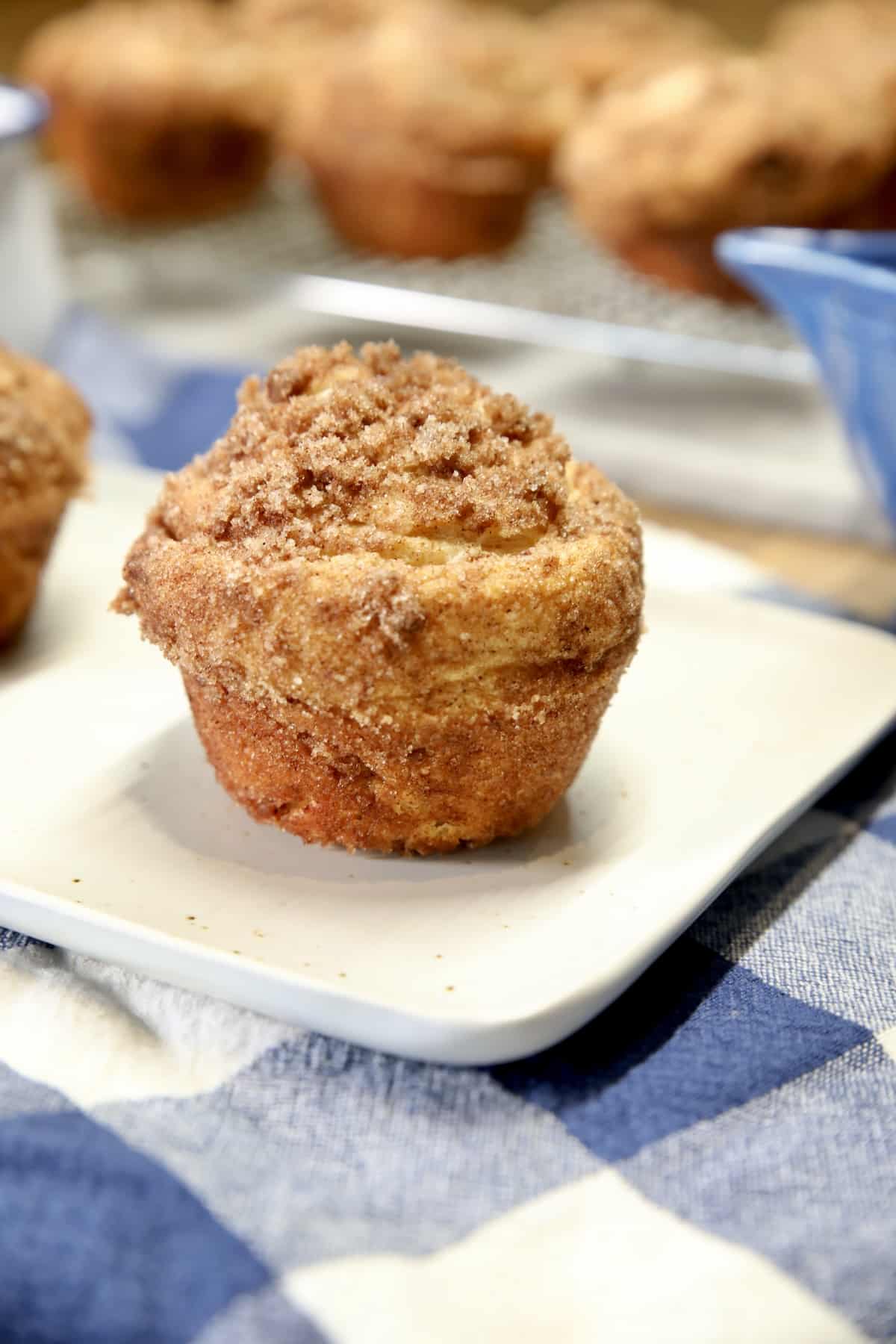 Sopapilla Cheesecake Cruffin on a small plate on a blue and white towel.