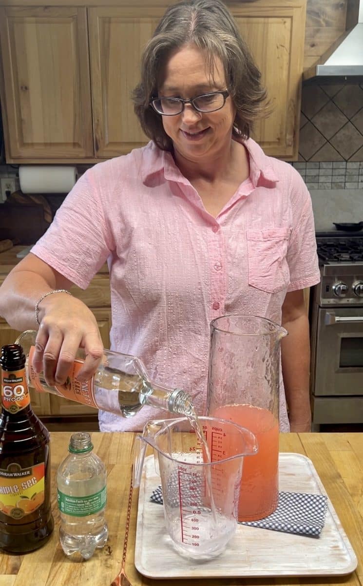 Measuring peach vodka for punch.