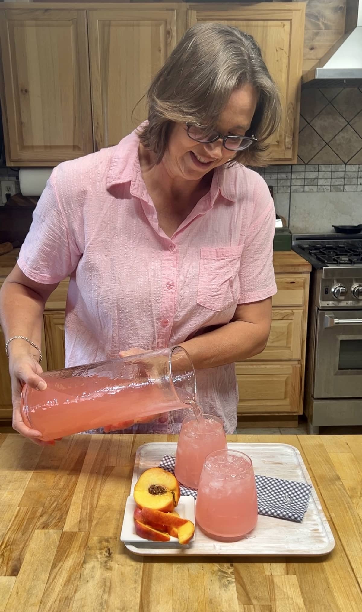 Pouring peach lemonade punch into glasses.