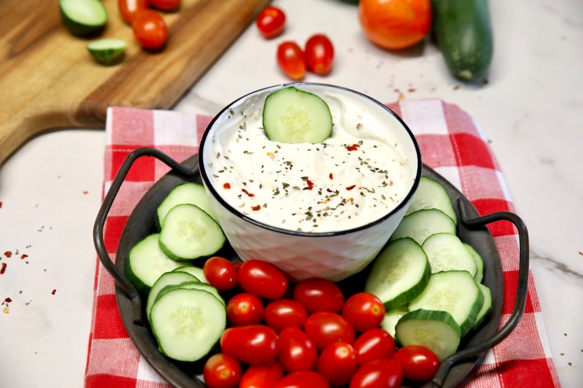 Greek yogurt dip with Italian dressing mix. Bowl of greek yogurt dip with cucumber slices and cherry tomatoes for dipping.