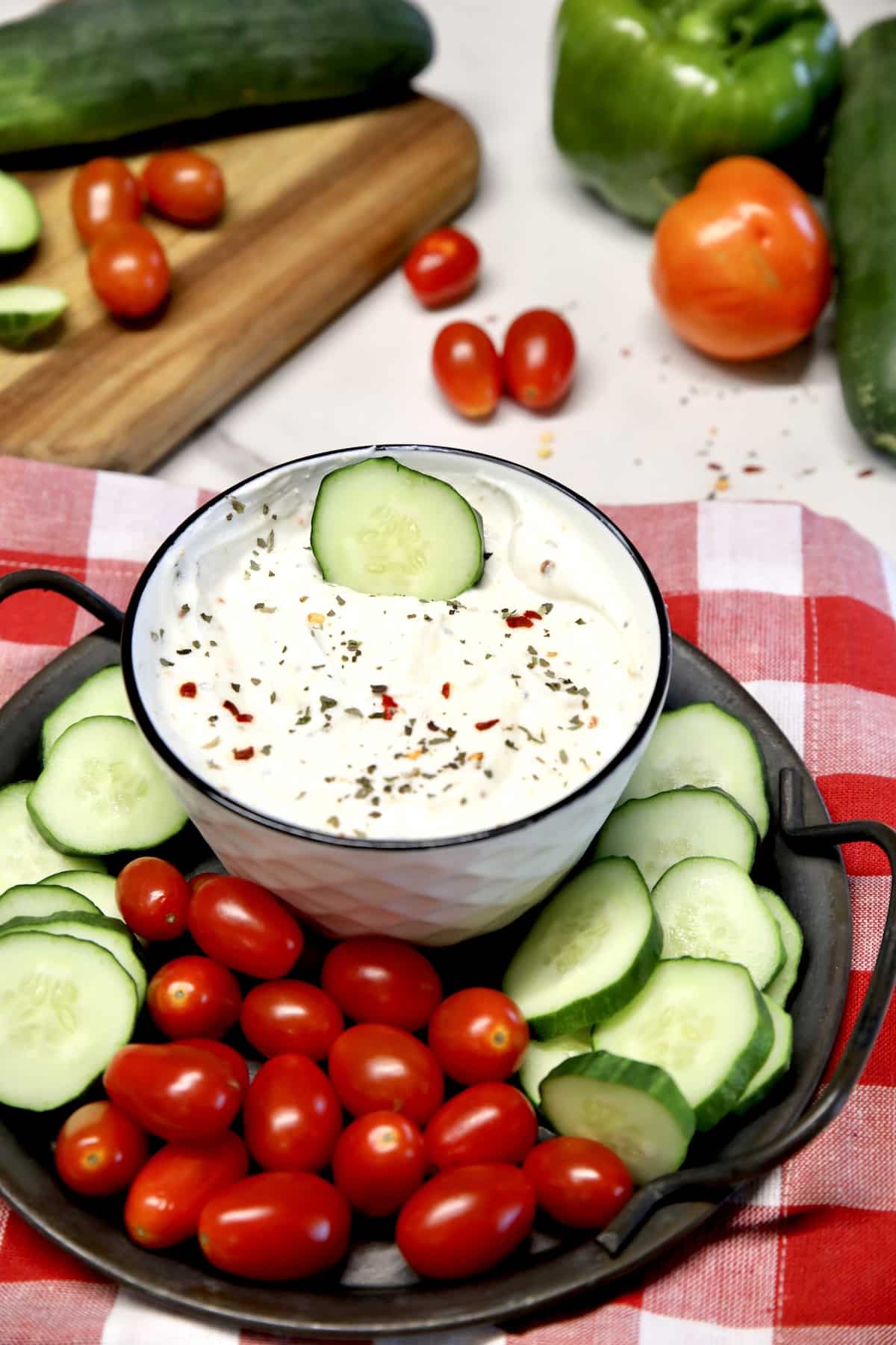 Platter of cucumber slices, tomatoes and veggie dip.