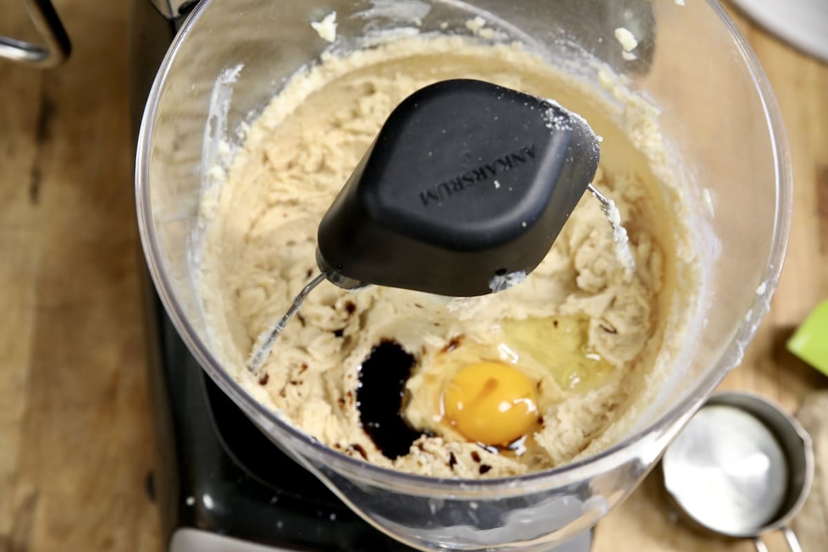 Adding egg and vanilla to cookie dough.